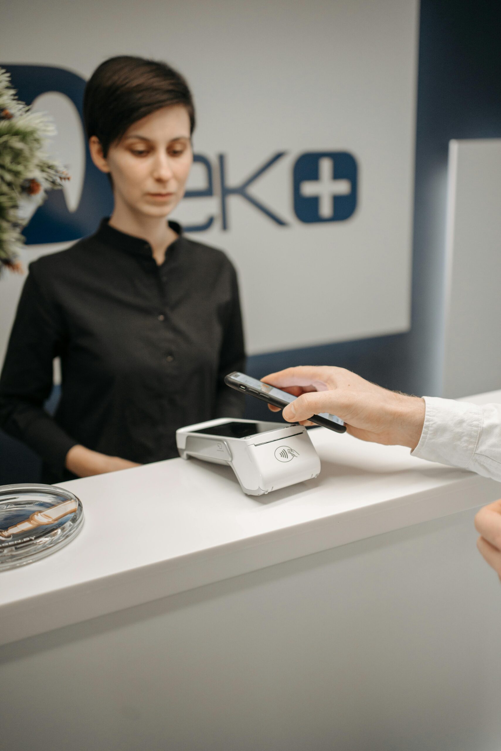 Home A woman witnesses a customer making a contactless payment using a smartphone at a service counter.